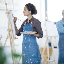 woman in apron painting at an easel
